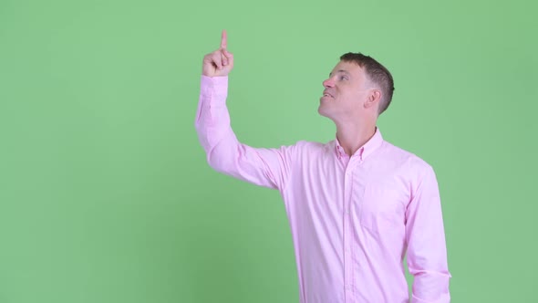 Portrait of Happy Businessman Pointing Up and Giving Thumbs Up