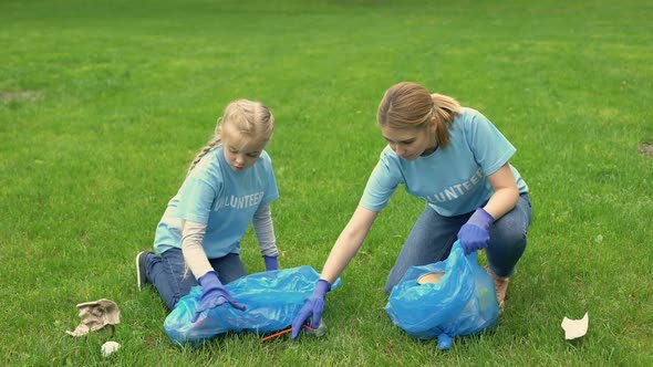 Young Woman and Schoolgirl Giving High Five Collecting Garbage in Park, Teamwork