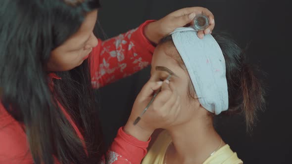 Close up of professional make up artist coloring the eyebrows on woman's face and doing the make up