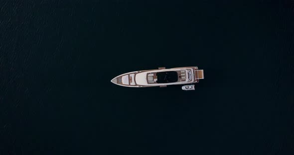 Aerial ascent over luxury yacht anchored in middle of the ocean; top-down