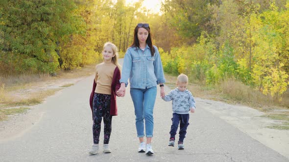 Beautiful Young Woman with Two Children Walking in Forest