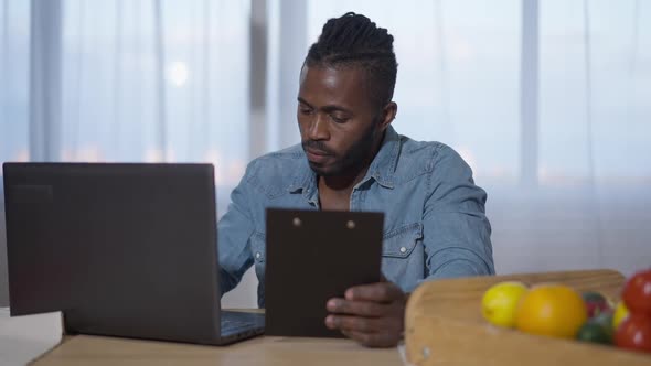 Confident African American Man Analyzing Business Market Surfing Internet on Laptop and Checking