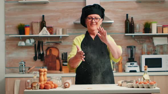 Baker Claps Her Hands with Flour Over the Table