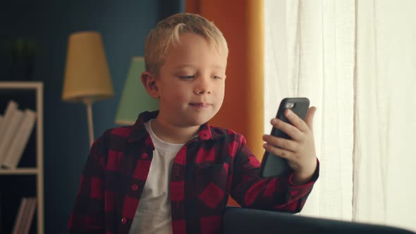 A Little Cute Boy is Talking Via Video Call Sitting in a Cozy Homelike Atmosphere