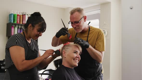 Side view woman having her hair styled by two hairdressers