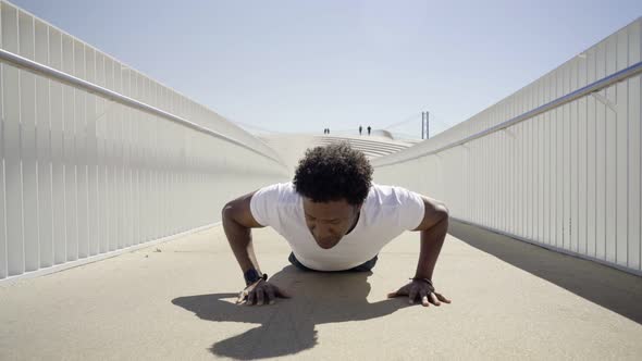 Focused Sporty Young Man Doing Push-ups on Bridge