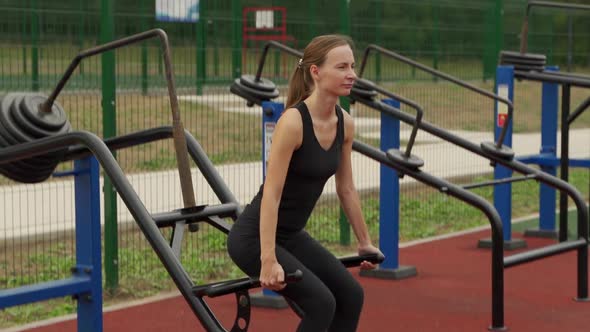 Young Fitness Woman Does a Heavy Deadlift in the Simulator at the Outdoor Sports Ground