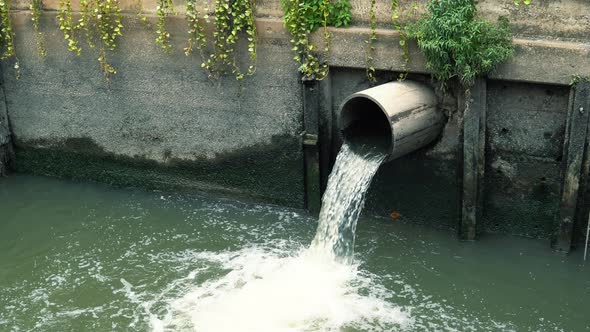 Wastewater flows down from sewer pipe and pollutes water in river at downtown