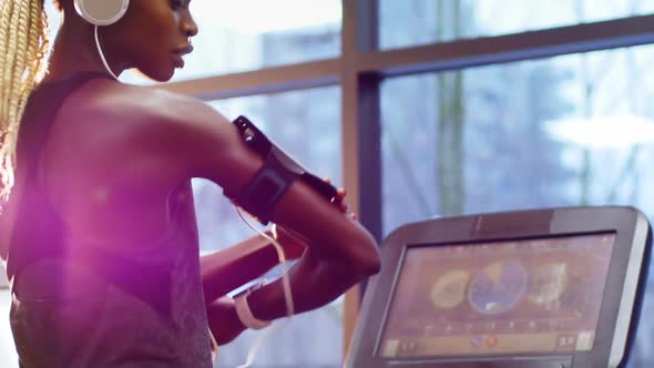 Fit woman with smartphone exercising on treadmill