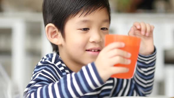 Cute Asian Child Drinking Water In The Glass 