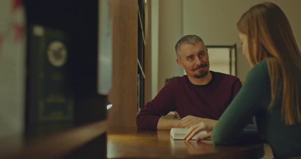 Handsome Man is Sitting at a Table with a Nice Woman Talking and Smiling at Her