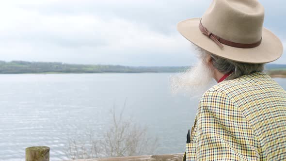 An elderly man looking out over the lake thinking about his history