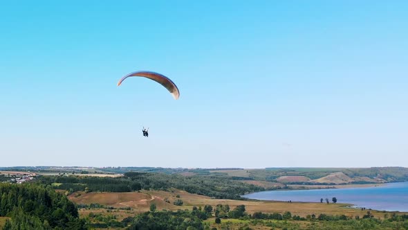 Tandem Flight on the Paraglider Above the Fields