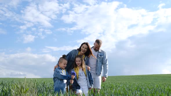 Happy Family of Farmers with Son and Daughter Walking on a Wheat Field