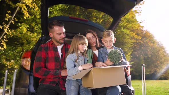 Smiling Satisfied Parents with Their Nice Children Sitting in the Auto's Trunk