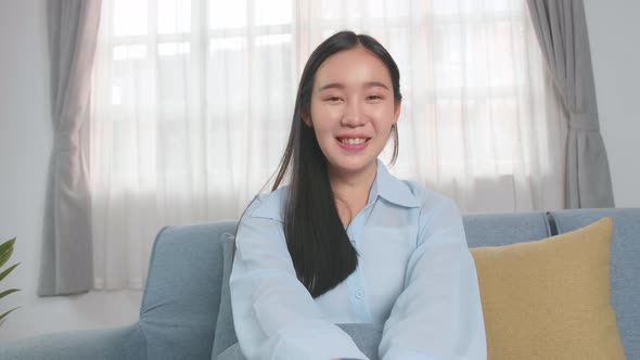 Asian Woman Talking To Camera In Home Living Room