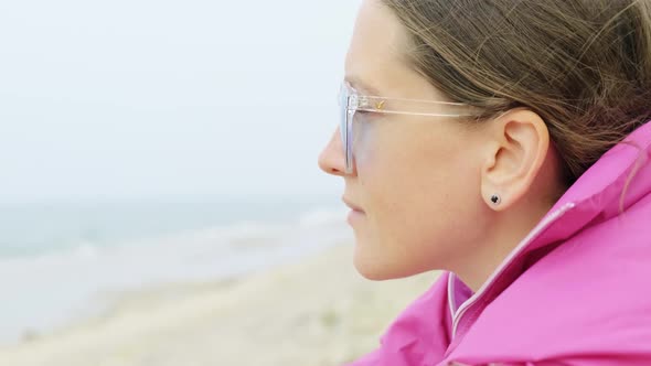 A Girl is Sitting on the Beach and Looking at the Sea