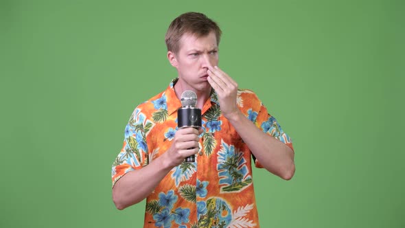 Young Handsome Tourist Man Talking on Microphone and Forgetting Something