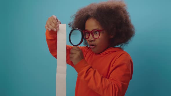 African American kid looking at large receipt with magnifying glass. Huge budget.