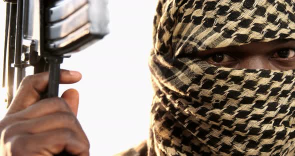 Terrorist holding machine gun against white background alt