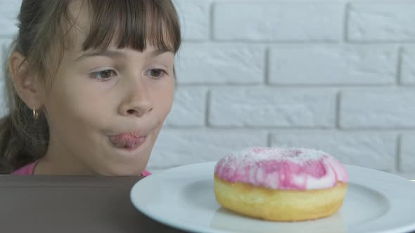Happy child looks at a donut. 