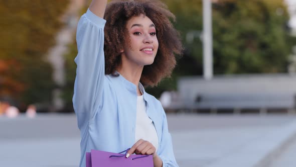 Young Active African American Girl Afro Woman Sitting Outdoors in City Peeping Someone Waving Hand