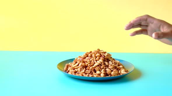 Hand Pick Processed Pea Nuts From a Plate on Color Background
