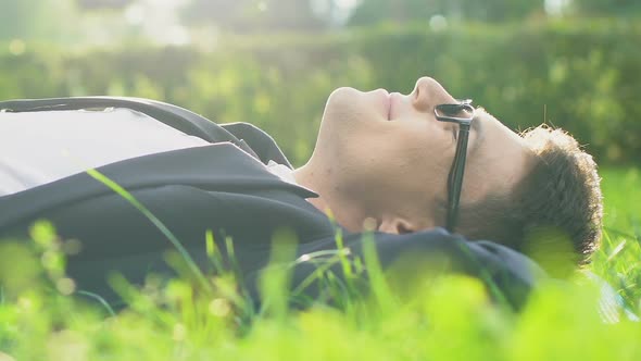 Male in Formal Wear Lying on Grass Enjoying Sunlight, Abstracting From Stress