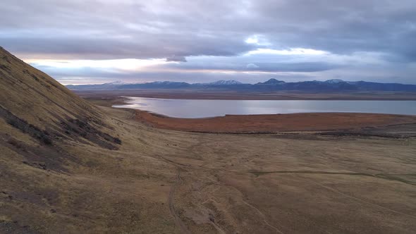 Flying over dirt road winding through vast landscape towards Utah Lake