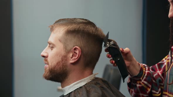 Barbershop: a woman barber cuts a client's man's hair