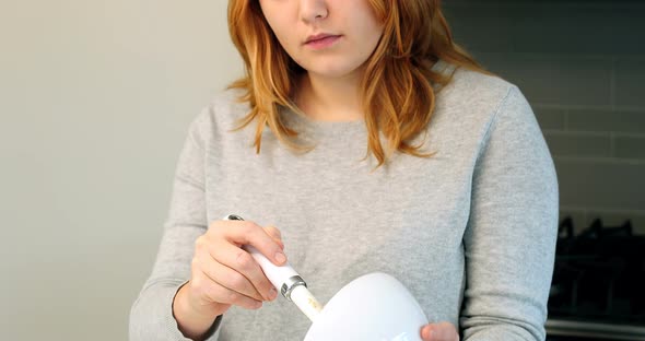 Woman adding ingredients to bowl for baking