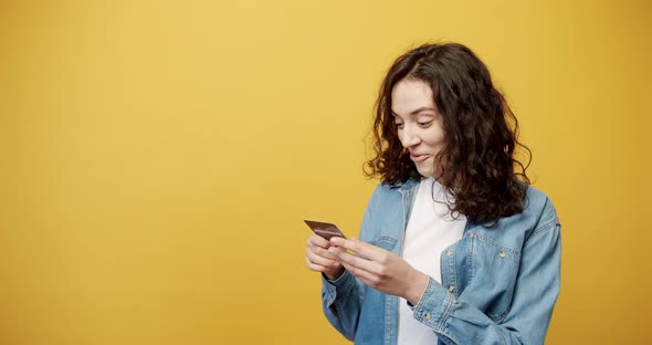 A Girl Receives a Credit Card and She is Happy Filmed Yellow Background Studio