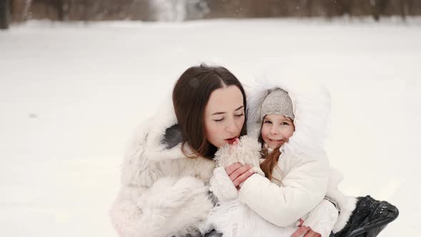 Mother Having Fun Sledding with Kids in Winter Forest