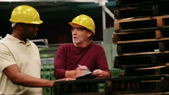 Workers writing on clipboard while interacting with each other