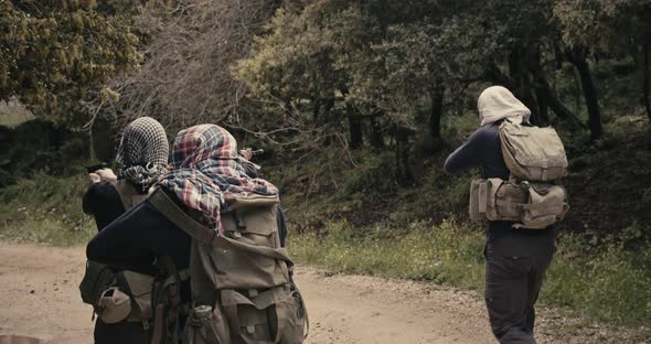 Squad of armed terrorists patrolling a forest area during combat alt
