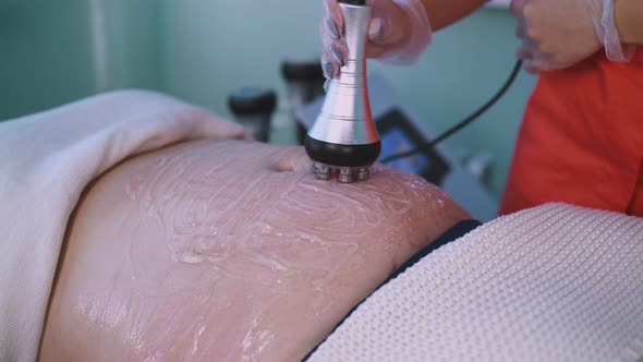 Woman Does Vibromassage To Plump Client in Clinic Closeup