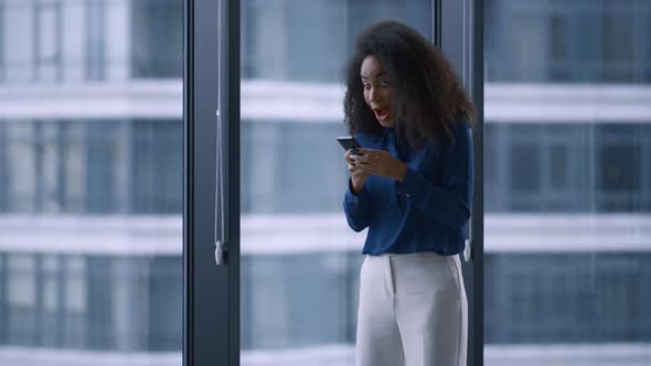 Excited African American Manager Woman Celebrating Good News on Phone in Office