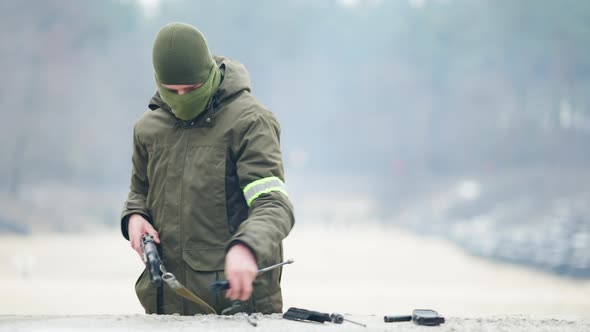 Professional Concentrated Caucasian Soldier Disassembling Rifled Gun and Putting Weapon Down