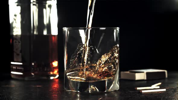 A Stream of Cognac Pours Into a Glass on the Table