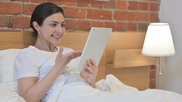 Young Indian Woman doing Video Call on Tablet in Bed