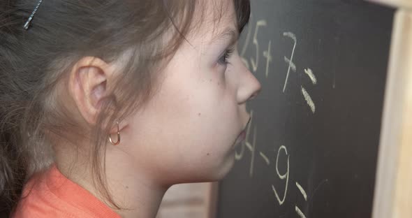 Child at elementary school by blackboard.