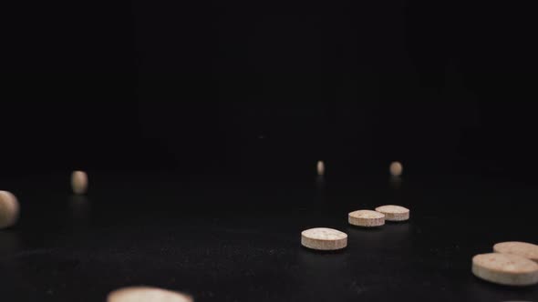 Throwing Small Beige Drug Pills To Pile on Black Surface