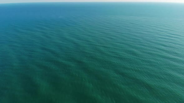 The Camera Flies Over the Sea Towards the Clear Horizon. The Camera's View Rises From the Sea