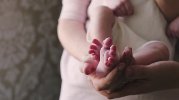 Feet of a Newborn in the Hands of Parents Close-up. Mom and Dad Are Holding a Newborn in Their Arms