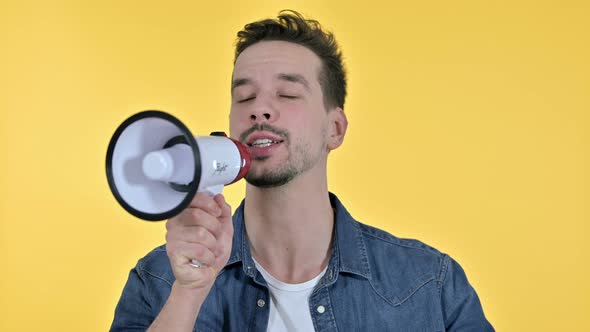 Portrait of Young Man Talking on Loudspeaker, Yellow Background