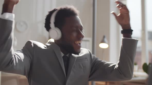 Happy Afro-American Businessman in Headphones Listening to Music at Work