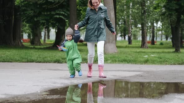 Funny Kid in Rain Boots Playing in a Rain Park