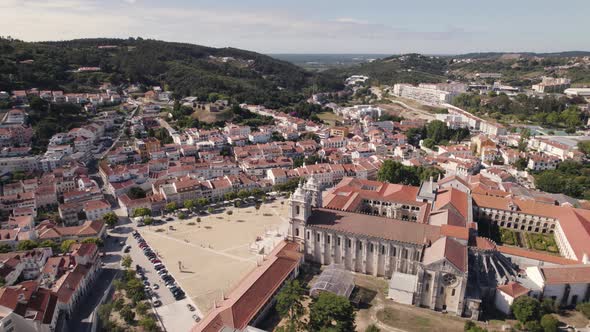 Orbiting shot of Mosteiro de Alcobaça against cityscape and forest, Portugal