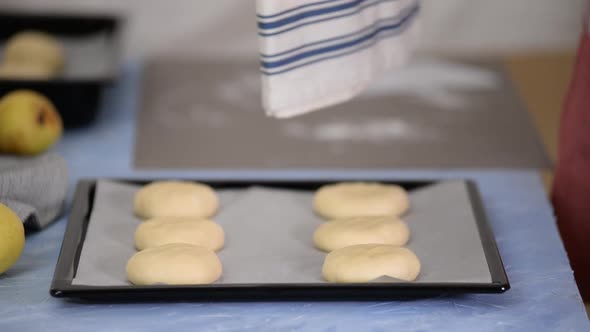 Female Hands Covered the Raw Buns with Kitchen Towel