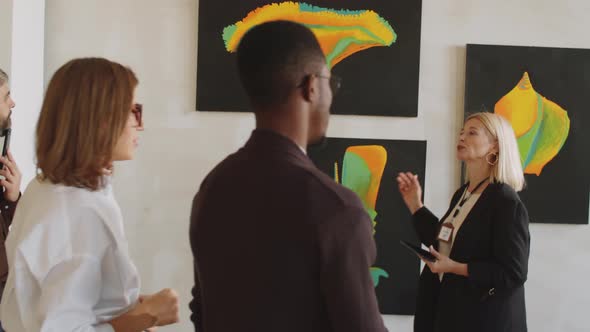 Female Gallery Guide Telling about Exhibition to Visitors